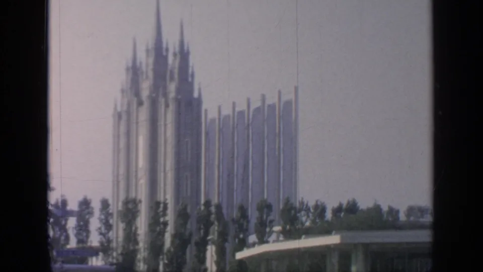 1964 Flushing Meadows view of tall pavilion spires partly obscured by trees, with a low building at the edge of frame.