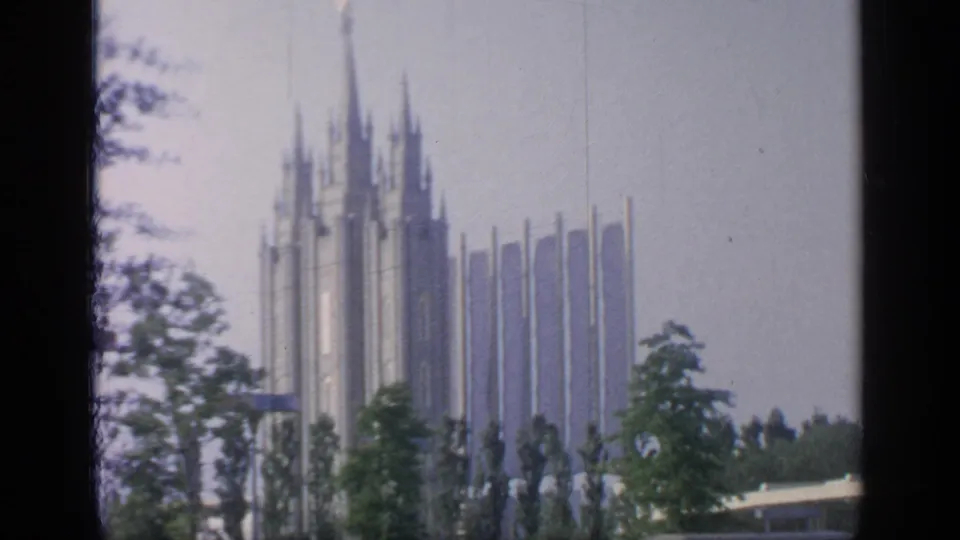 Tall spired World's Fair pavilion architecture appears behind trees at Flushing Meadows in the supplied 1964 setting.