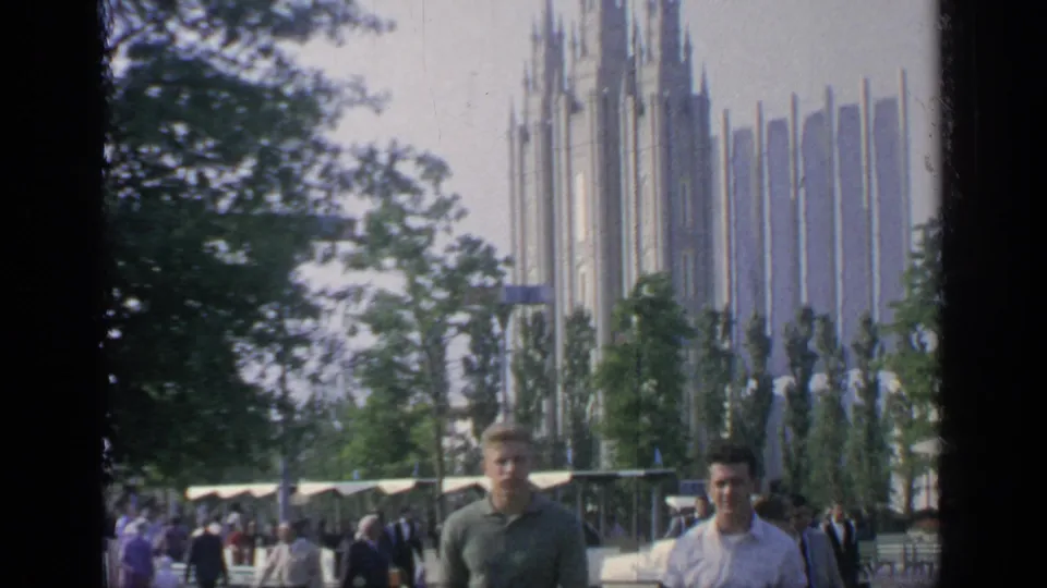 Visitors in period clothing pass near a spired pavilion at the 1964 Flushing Meadows World's Fair grounds.