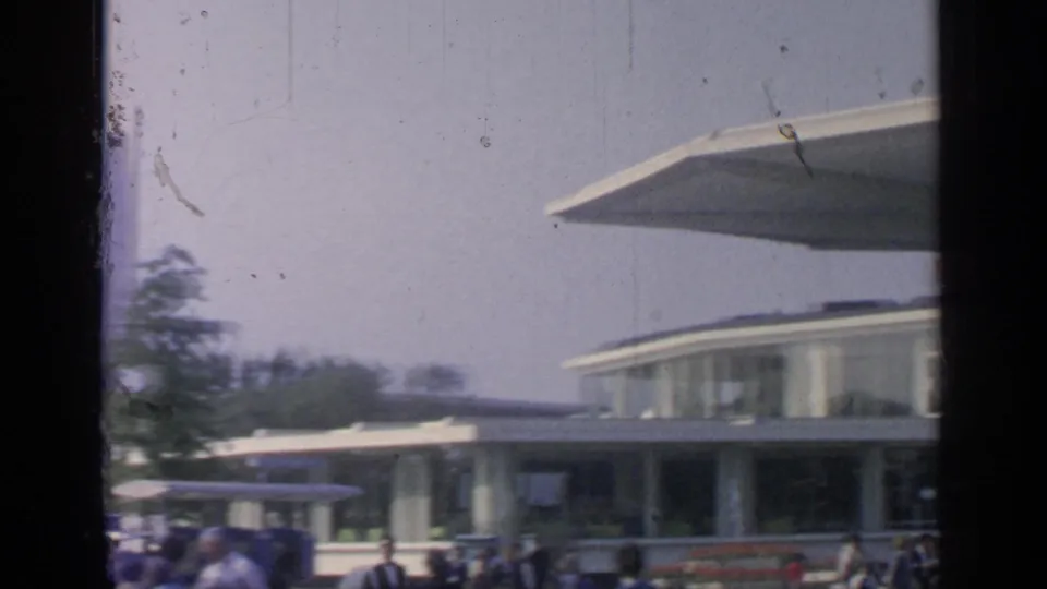 Modernist fairground canopy and low glass-fronted building with visitors below, consistent with the supplied 1964 Flushing Meadows context.