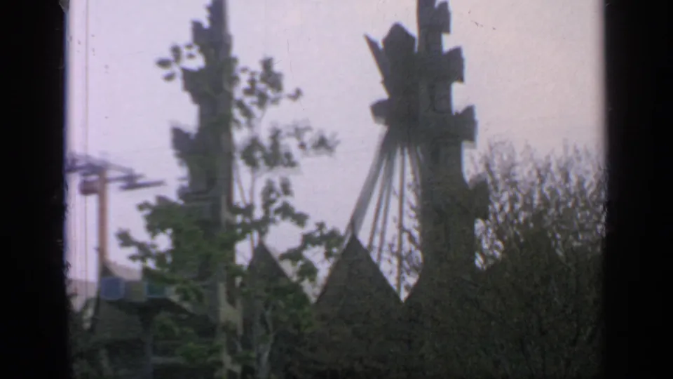 Flushing Meadows fairground frame showing a tall cable car tower, trees, and Indonesia Pavilion roof peaks in 8mm softness.