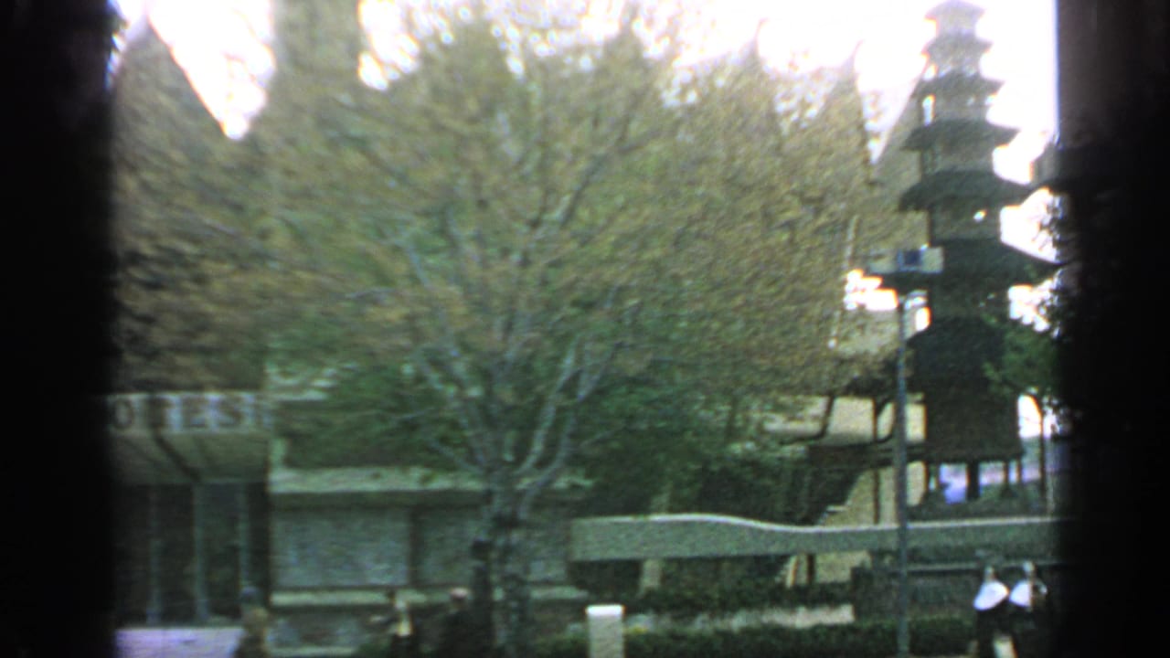 Japanese-style pagoda structure beside trees and pavilion buildings in a fairground setting.