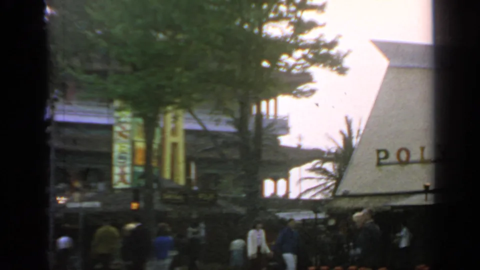 1964 Flushing Meadows World's Fair view of the Polynesian Restaurant exterior, trees, and fair visitors in soft 8mm color.
