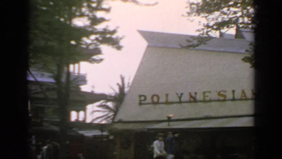 A closer 8mm frame shows the Polynesian Restaurant lettering across the roof, with trees and fair visitors near the entrance area.