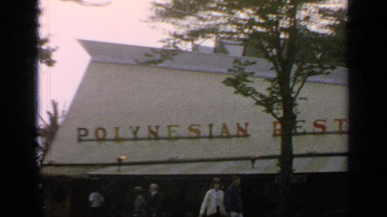Restaurant exterior with Polynesian lettering, trees, awning, pedestrians, and dark film borders.