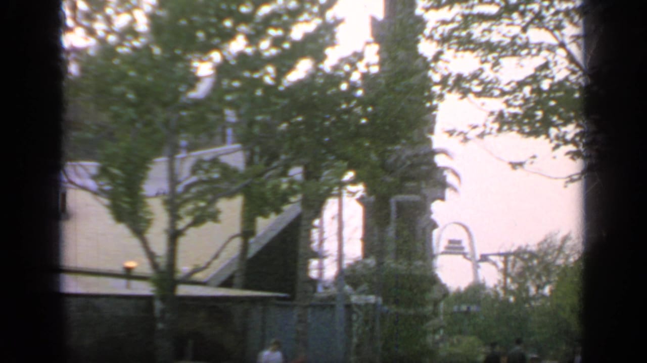 Trees and a large arched fair building with small figures in the distance.