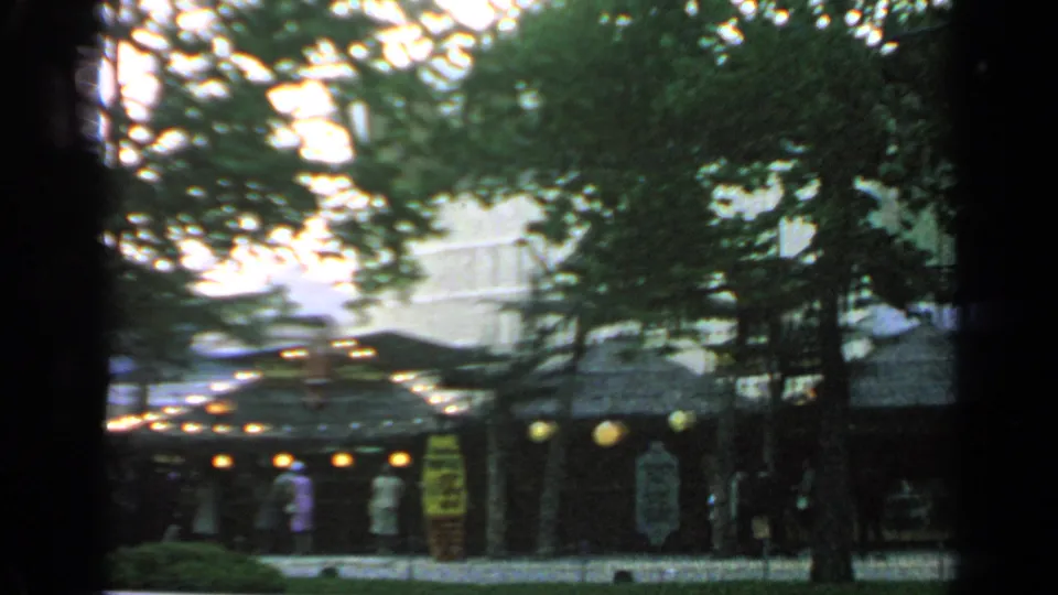 A home-movie view of the Flushing Meadows market area shows thatched stalls, yellow signage, lanterns, and visitors in 1960s dress.