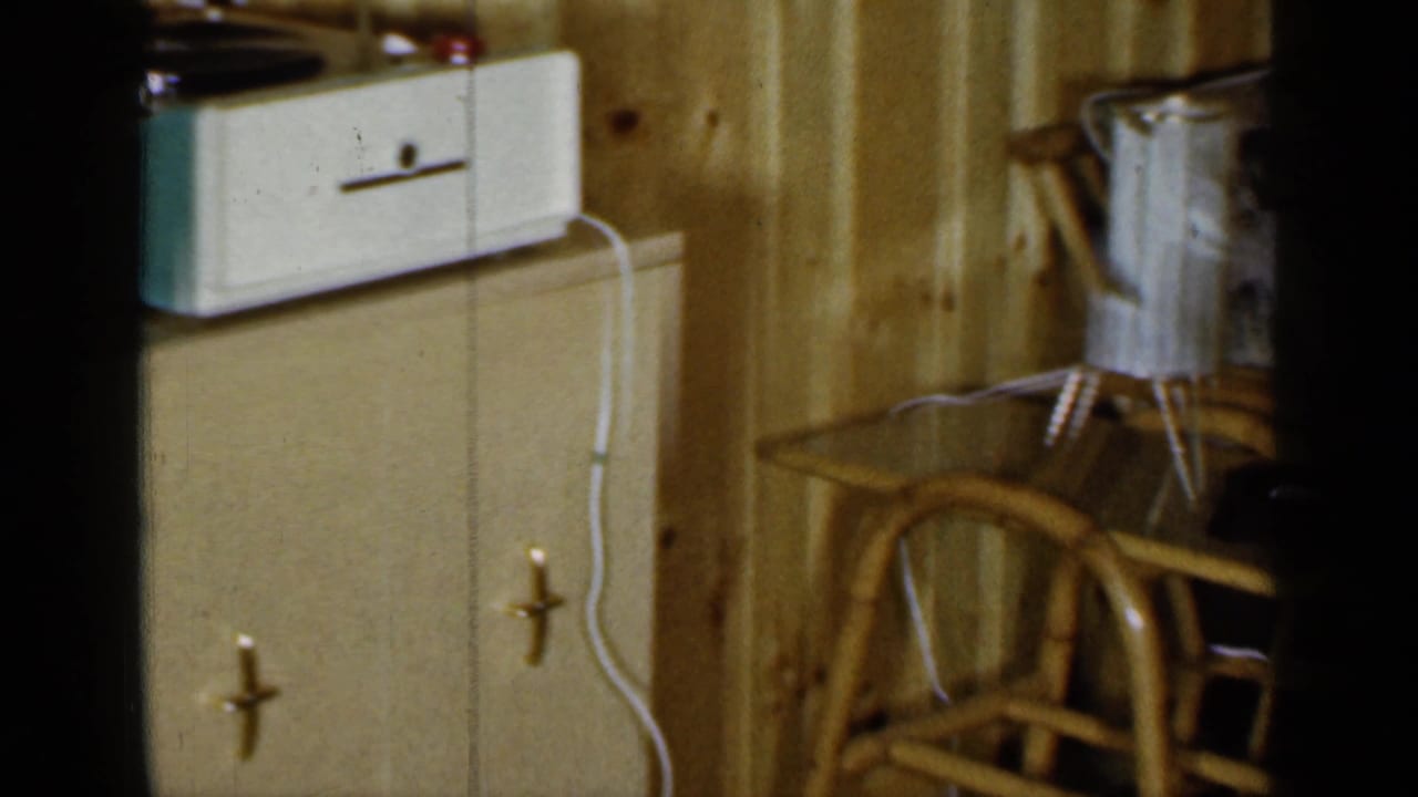 Record player, cabinet, wood wall, and rattan furniture in a private room.
