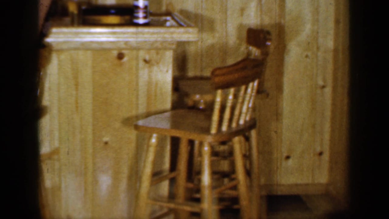 Empty wooden bar stools beside a wood-paneled bar counter with bottles and glasses.