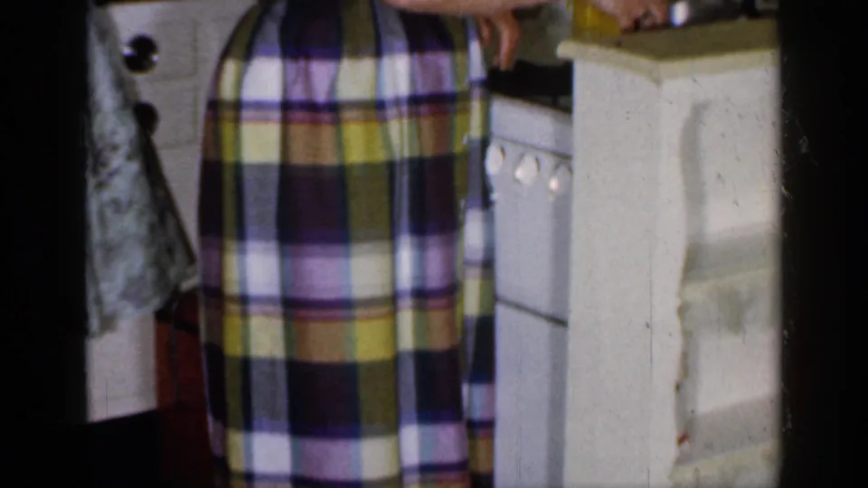 Close 1965 Long Island home-movie view of a plaid skirt next to a white stove, cabinet, and kitchen counter.