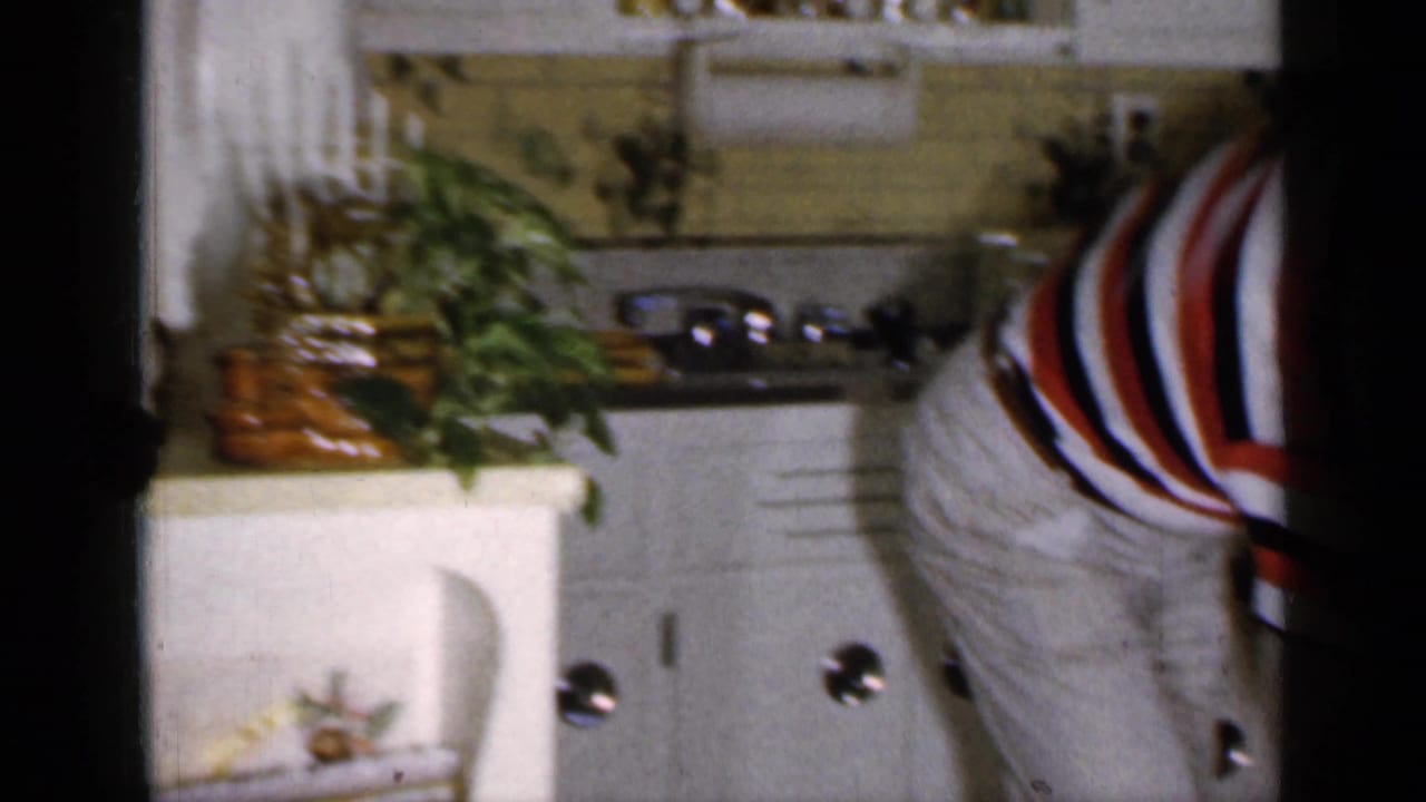 Man in a striped shirt bends near a white oven in a kitchen.