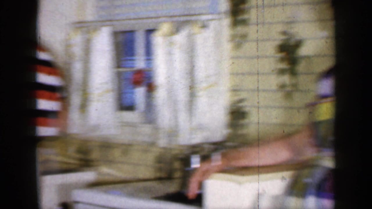 Blurred kitchen scene with a woman in a plaid dress near a sink and window.