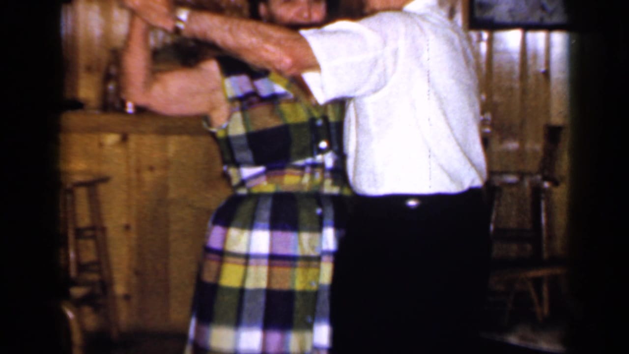 Man and woman dancing closely in a wood-paneled bar interior.