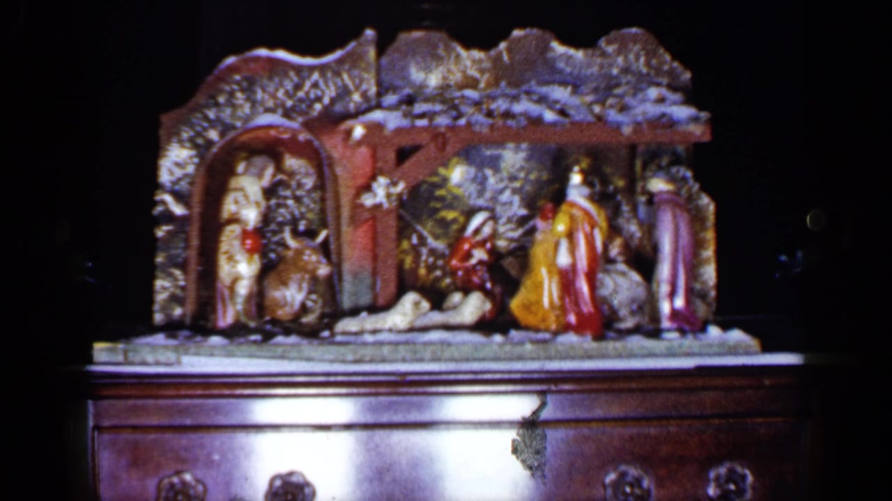 Ceramic manger display with colorful figures and animals resting on a wooden cabinet.