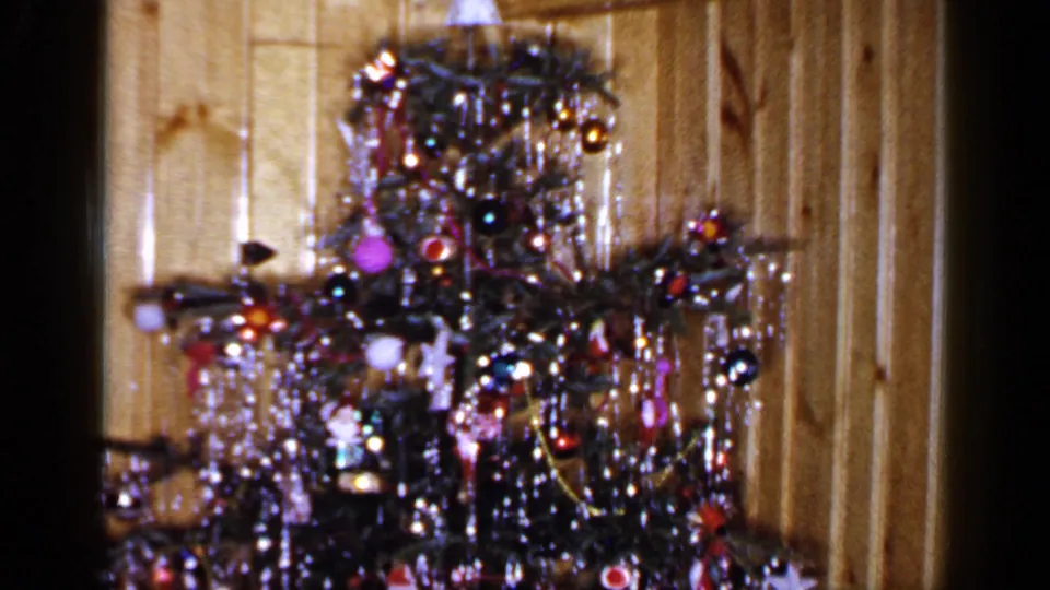 A 1965 Long Island home-movie frame holds on the decorated Christmas tree, angel topper, and warm paneled interior.