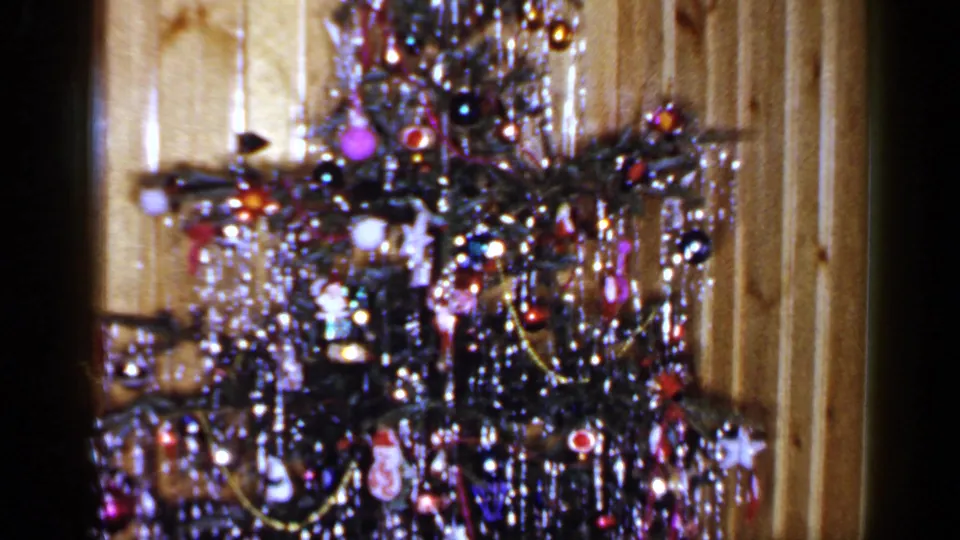 1965 Long Island home-movie frame with a closer view of tinsel, ornaments, lights, and garlands on the Christmas tree.