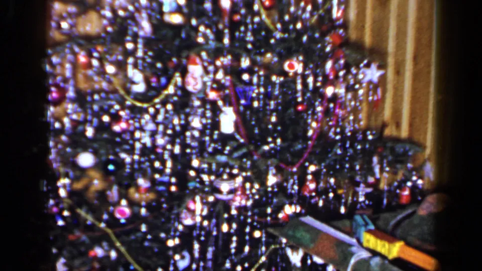 1965 Long Island holiday interior with a decorated Christmas tree and toy train pieces near the lower edge.