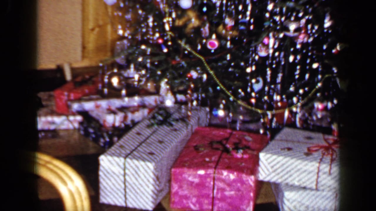 1965 Long Island frame with wrapped presents, tinsel, ornaments, and a light-toned cabinet near the Christmas tree.