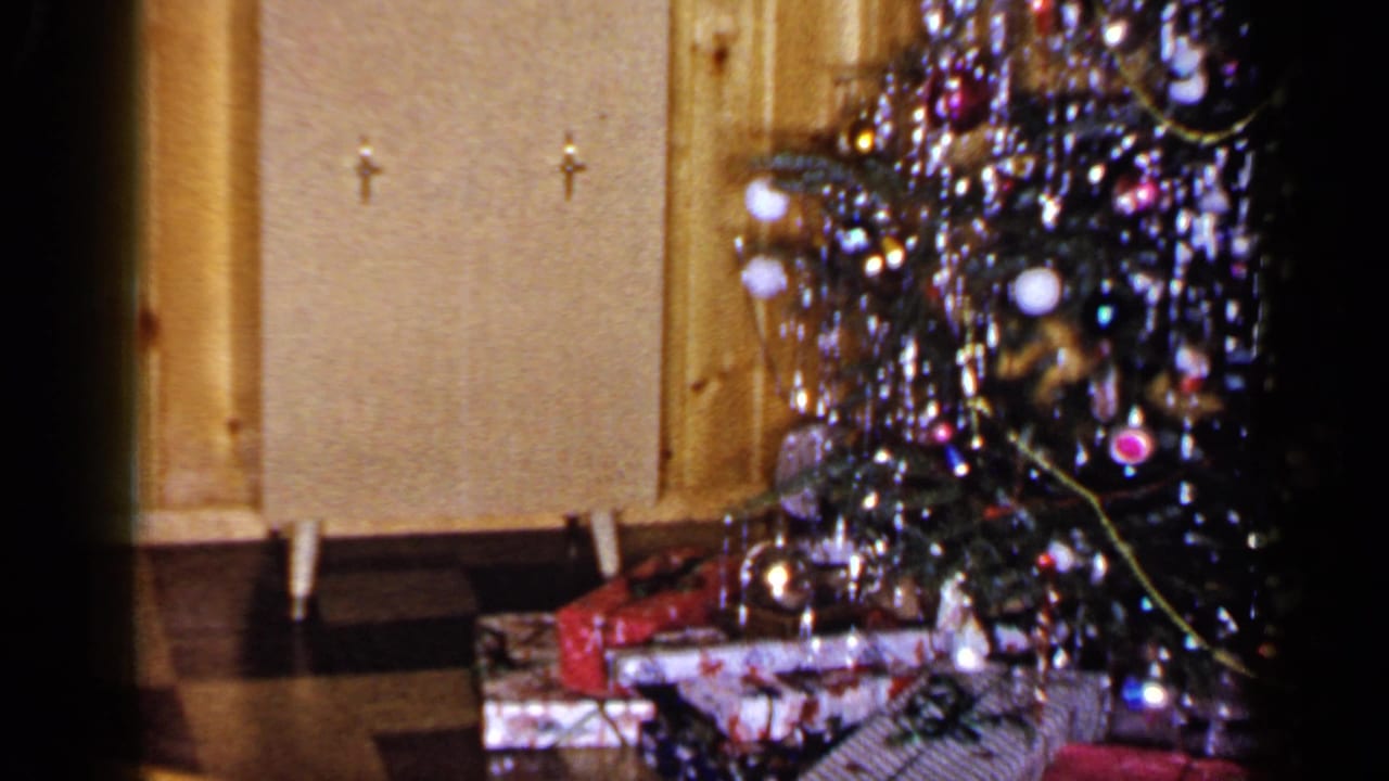 1965 Long Island home interior showing the Christmas tree edge, tinsel, ornaments, cabinet doors, and presents below.