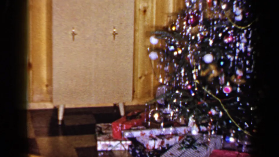1965 Long Island home interior showing the Christmas tree edge, tinsel, ornaments, cabinet doors, and presents below.
