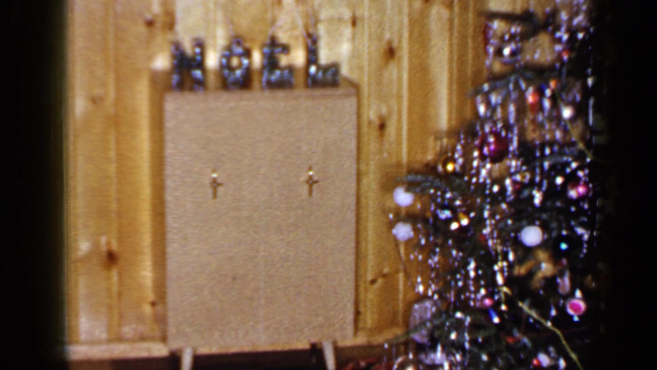 1965 Long Island interior with a NOEL display on a cabinet and a tinsel-covered Christmas tree partly visible at right.