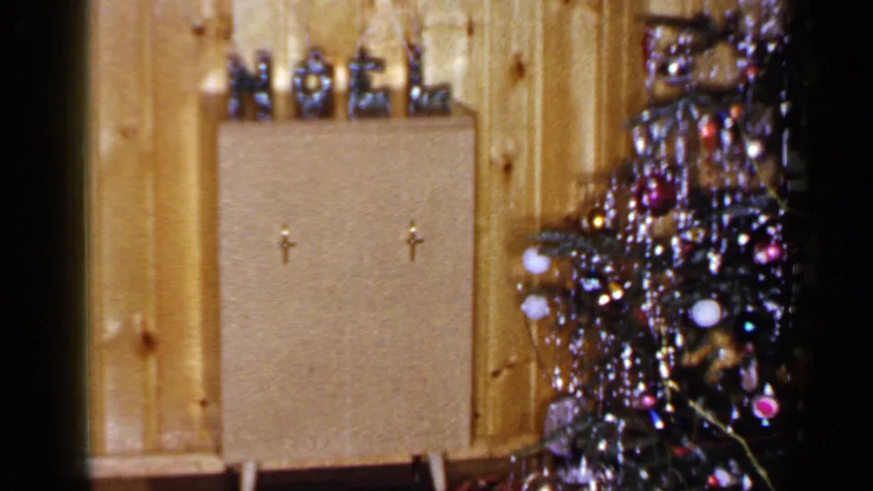 1965 Long Island interior with a NOEL display on a cabinet and a tinsel-covered Christmas tree partly visible at right.