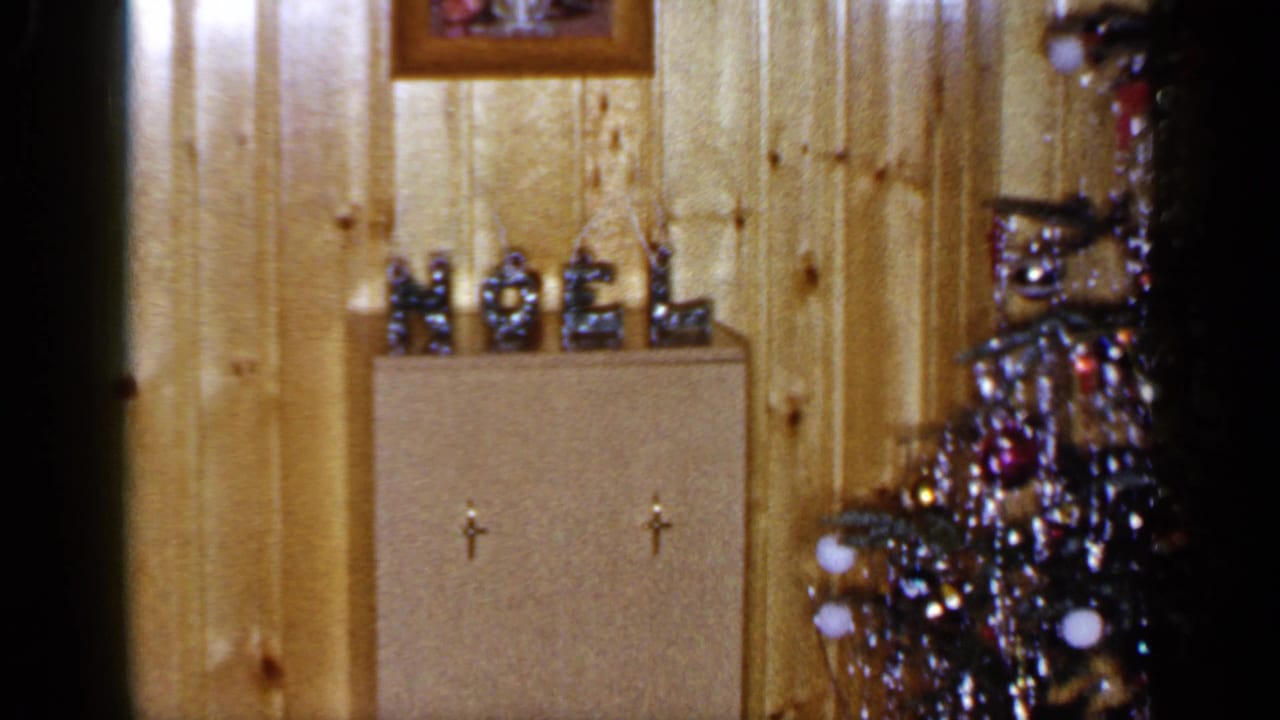 1965 Long Island home interior showing a small NOEL display, cabinet doors and part of a decorated Christmas tree.