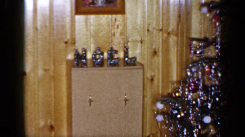 1965 Long Island home interior showing a small NOEL display, cabinet doors and part of a decorated Christmas tree.