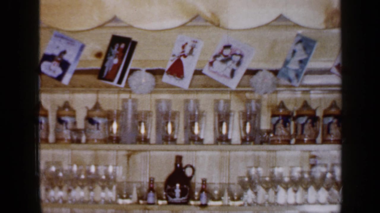 1965 Long Island interior detail showing pine shelves, hanging holiday cards, paper decorations, steins, glassware, and dark jugs.