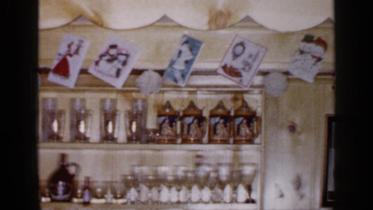 The 8mm pan continues across a Long Island Christmas display with hanging cards, pom-pom garland, glassware, and decorative steins.