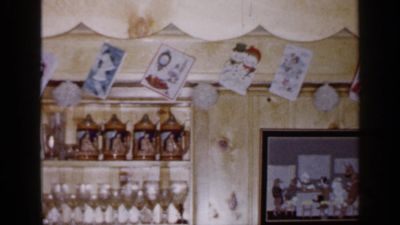 A Long Island holiday wall display includes Christmas cards, glassware, beer steins, and a framed picture with people visible inside it.