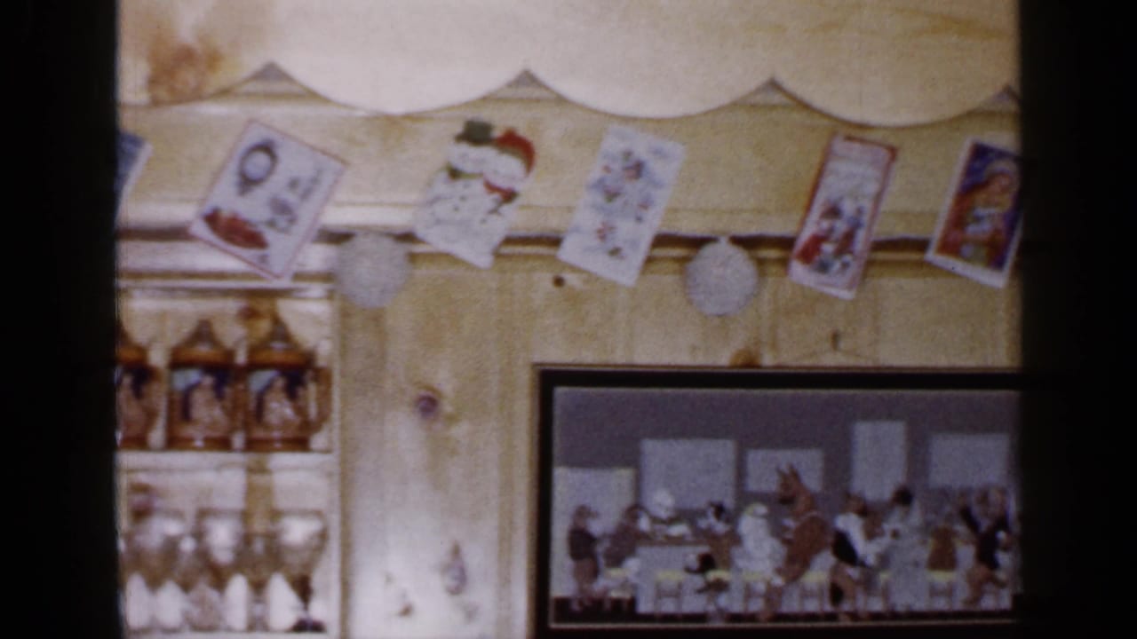 The pan ends on the right side of the 1965 Long Island Christmas display, with cards, garland, steins, glasses, and a framed gathering picture.