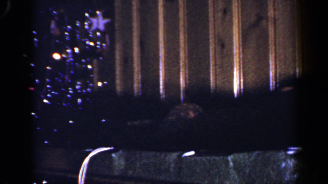 1965 Long Island Christmas interior with a blue-lit tree, star topper, dark seating, and vertical wood-paneled wall.