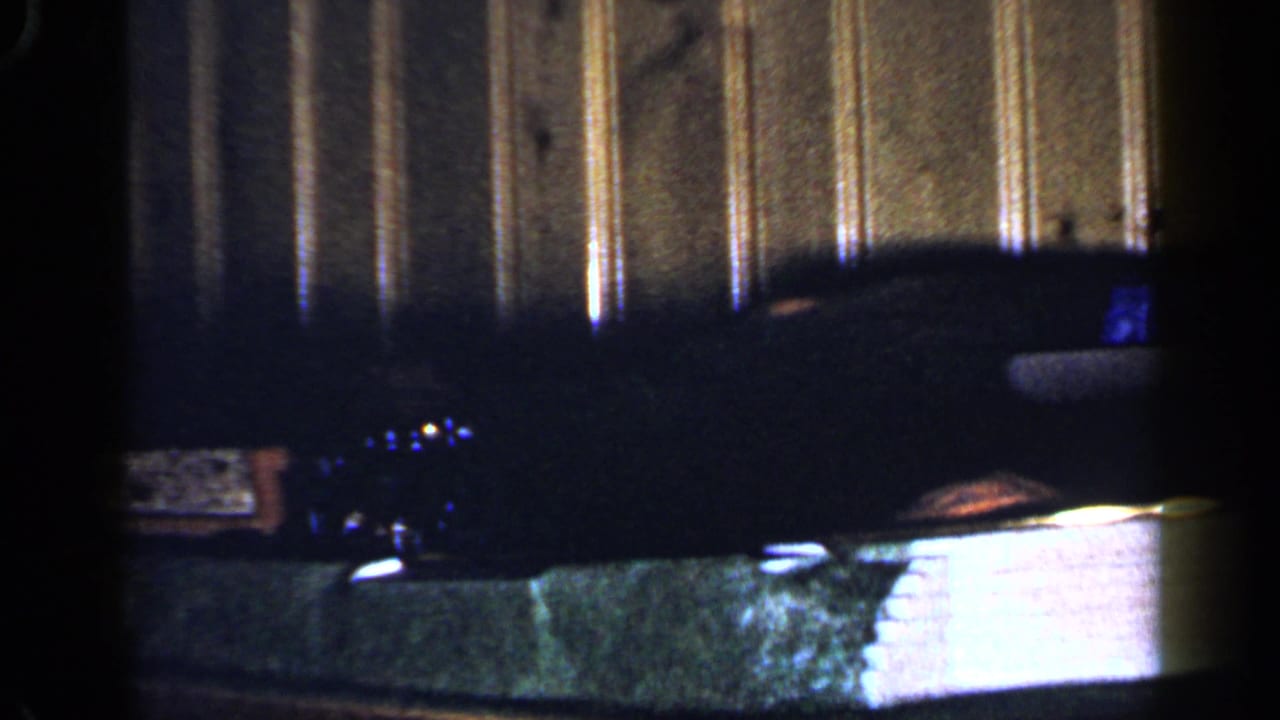 Toy train scene with a small lit train area against vertical wood paneling.