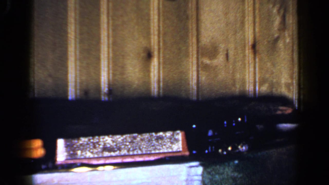 1965 Long Island 8mm frame showing the red toy coal car and black engine on a small indoor train setup.