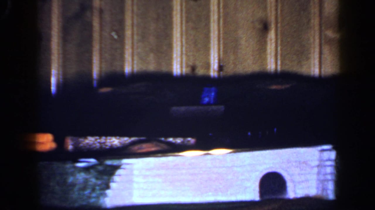 Dark furniture edge above a bright lower area with a small arched object in front.