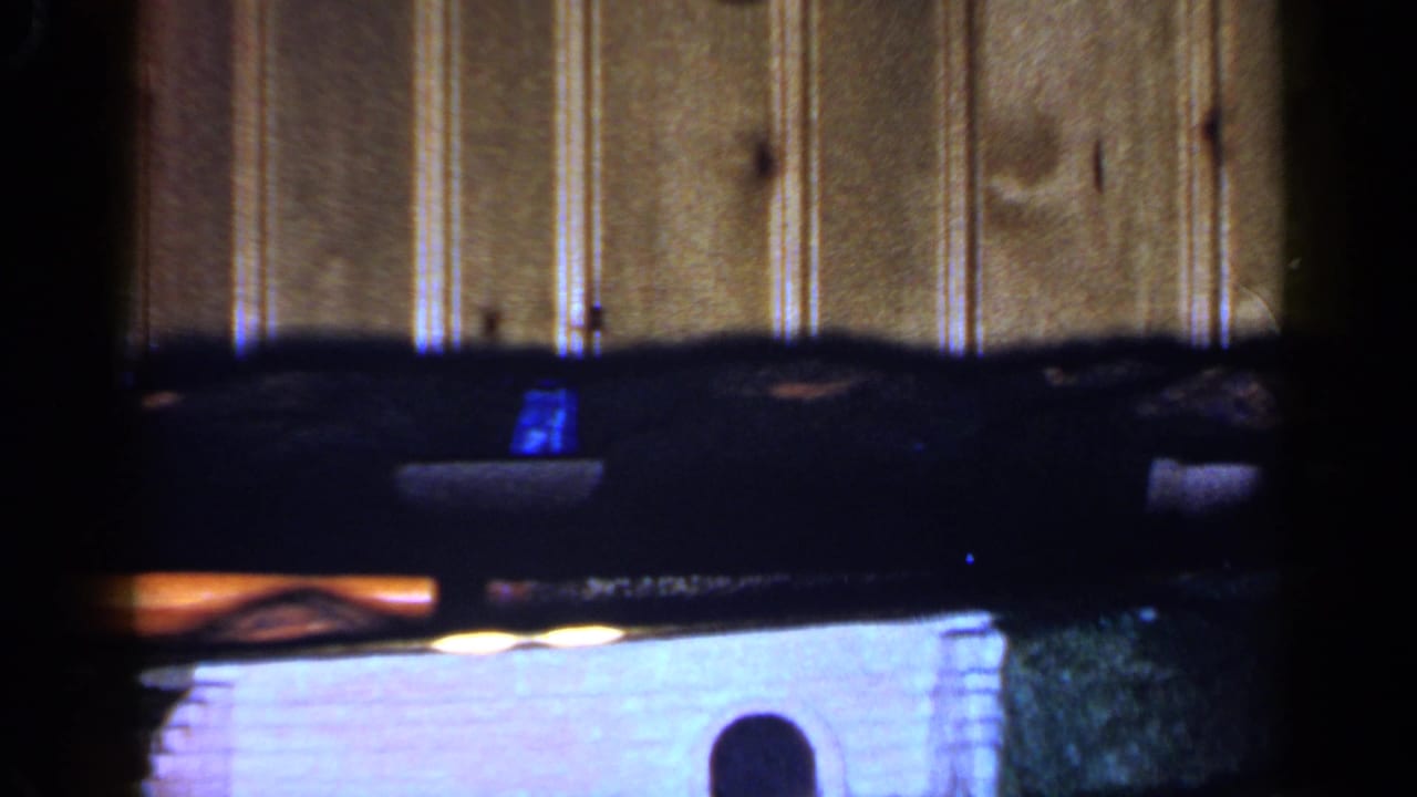 Dark upper furniture edge, bright lower surface, and small arched object in a dim room.