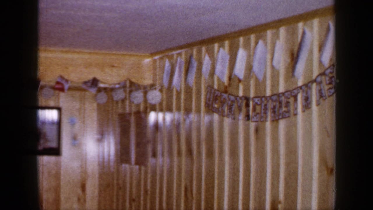 1965 Long Island home interior with wood paneling, handmade holiday decorations, small flags, and a framed family photograph on the wall.