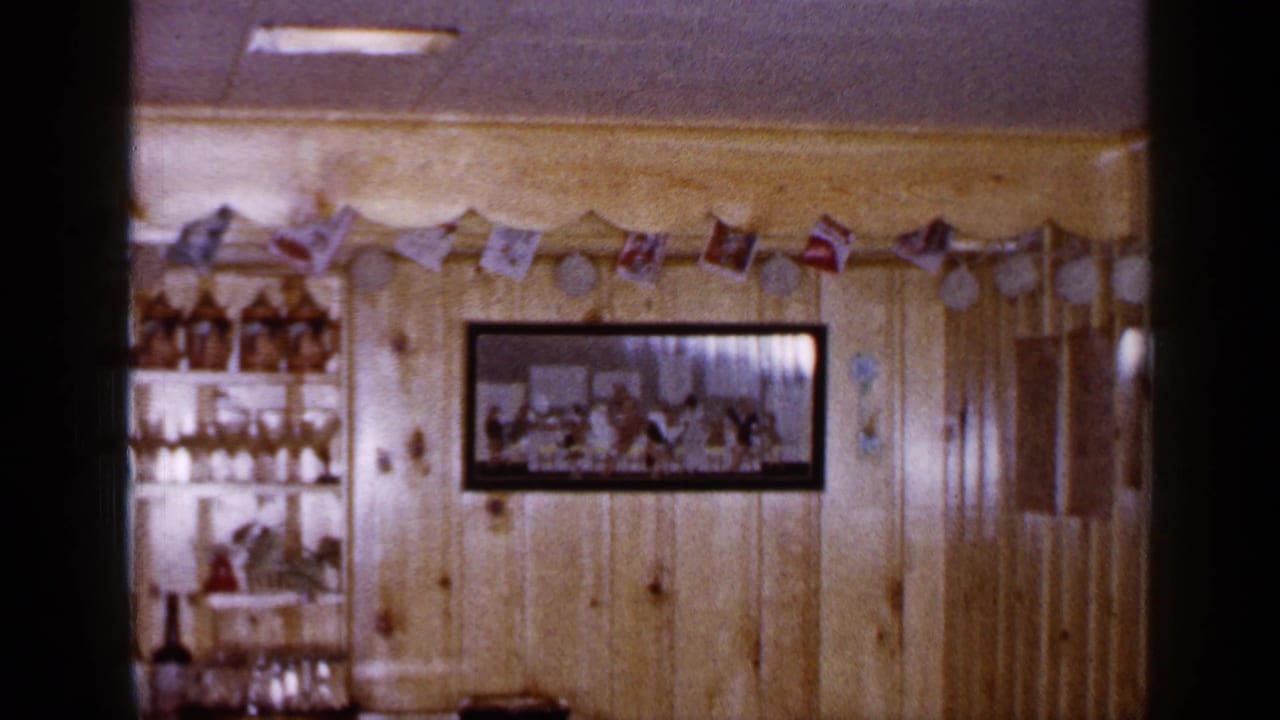 Long Island home interior decorated for Christmas, with a framed wall photograph, garland, flags, and a shelving unit holding glassware.