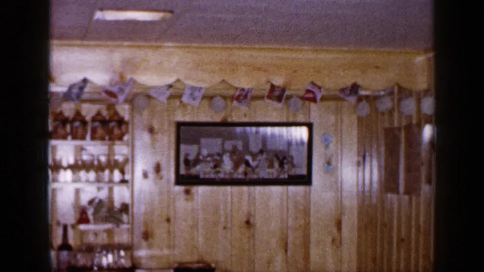 Long Island home interior decorated for Christmas, with a framed wall photograph, garland, flags, and a shelving unit holding glassware.