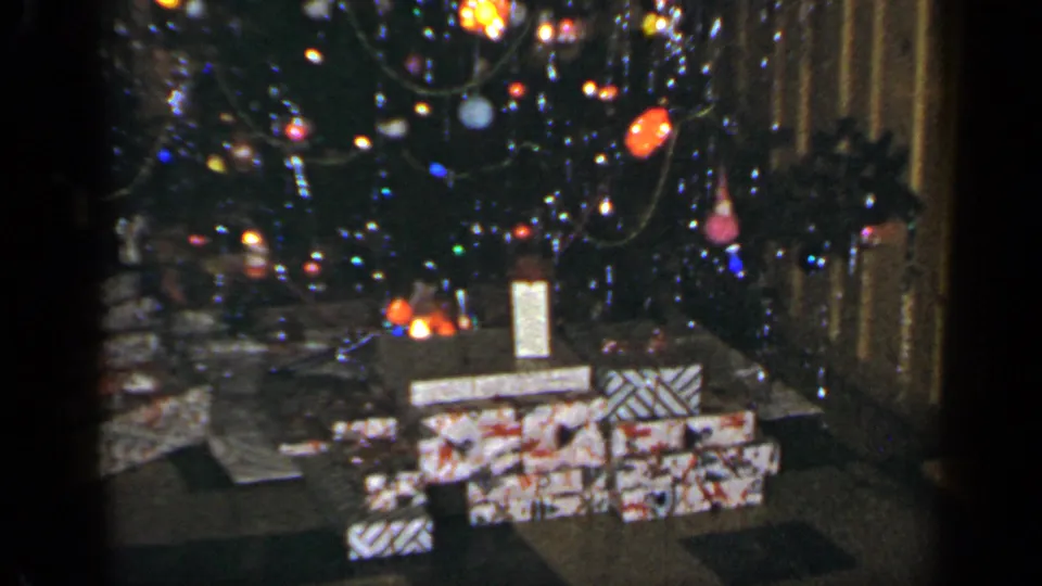 1965 Long Island Christmas tree with colored lights, ornaments, garland, and stacks of wrapped gifts on the floor.