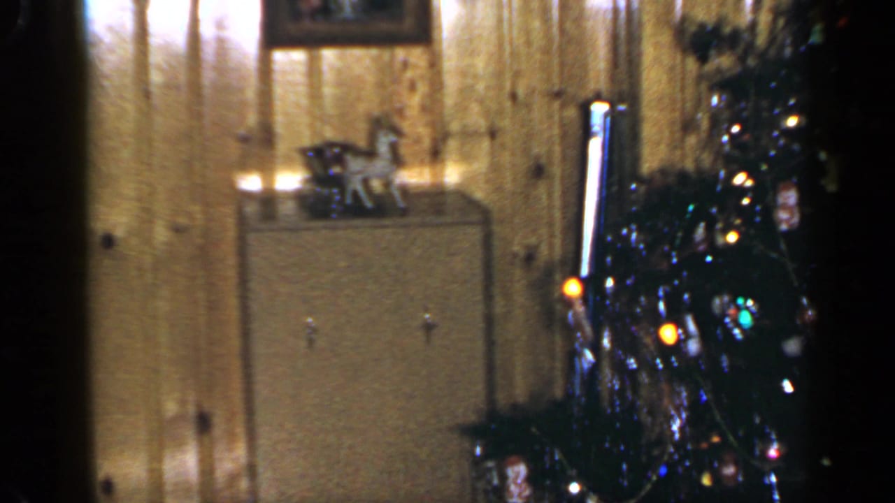 1965 Long Island frame with a decorated Christmas tree, warm lights, wrapped gifts, and mid-century cabinet in a private living room.