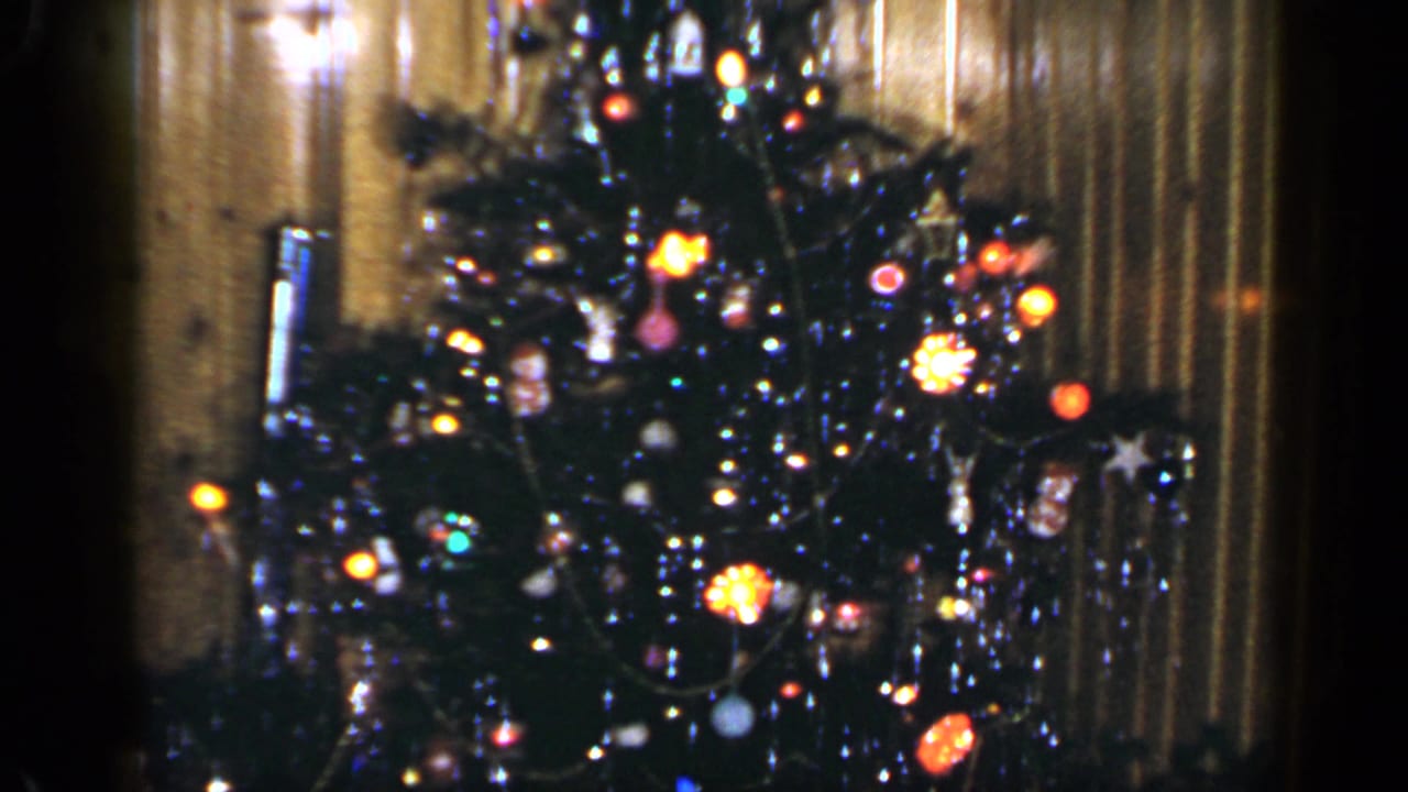 Soft 8mm frame of a decorated Christmas tree with bright bulbs and tinsel in a Long Island home.