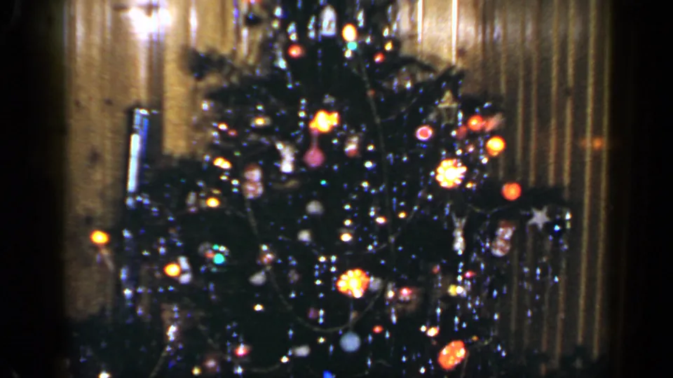 Soft 8mm frame of a decorated Christmas tree with bright bulbs and tinsel in a Long Island home.