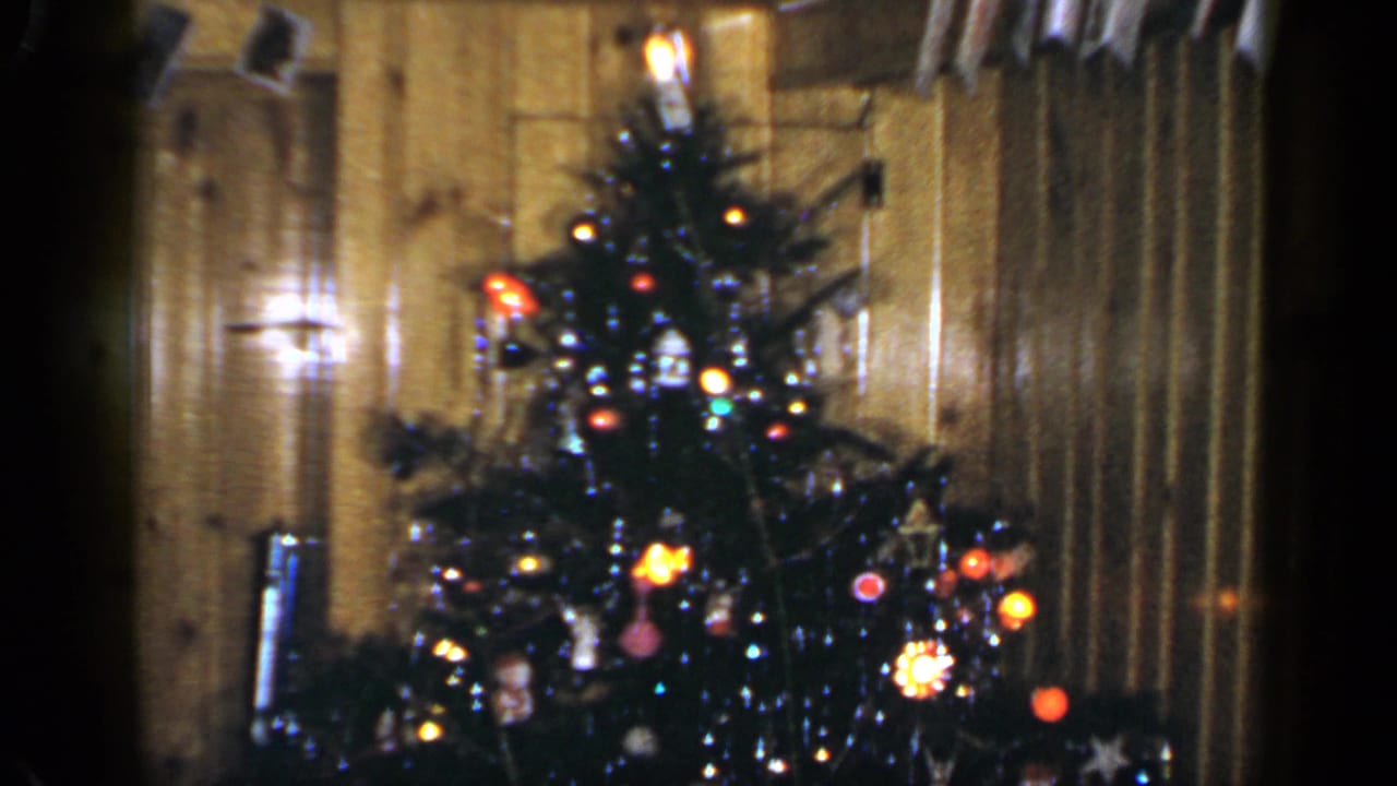 1965 Long Island home interior with a lit Christmas tree, ornaments, curtains, and warm wood paneling.