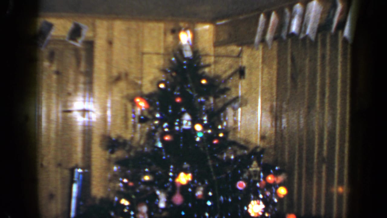 1965 Long Island holiday interior showing a Christmas tree beneath a row of hanging cards or photos.