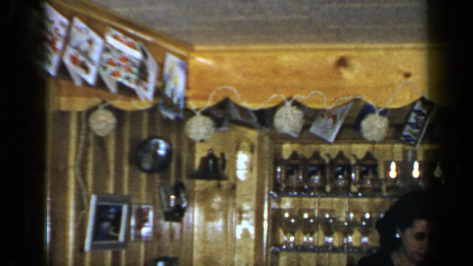 The camera drifts across a warm wood-paneled Long Island shop interior with glass shelves, hanging photographs, and the woman partly visible at the edge.