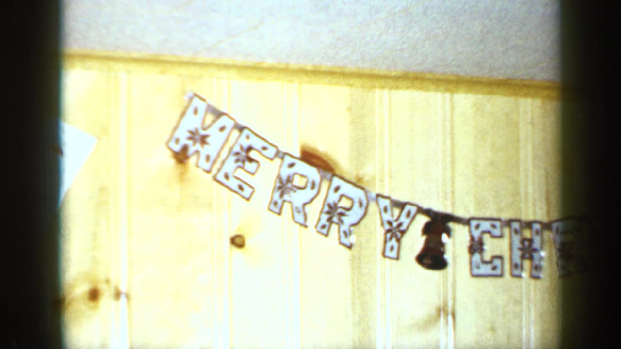Merry Christmas banner hanging on a pale wood-paneled wall.