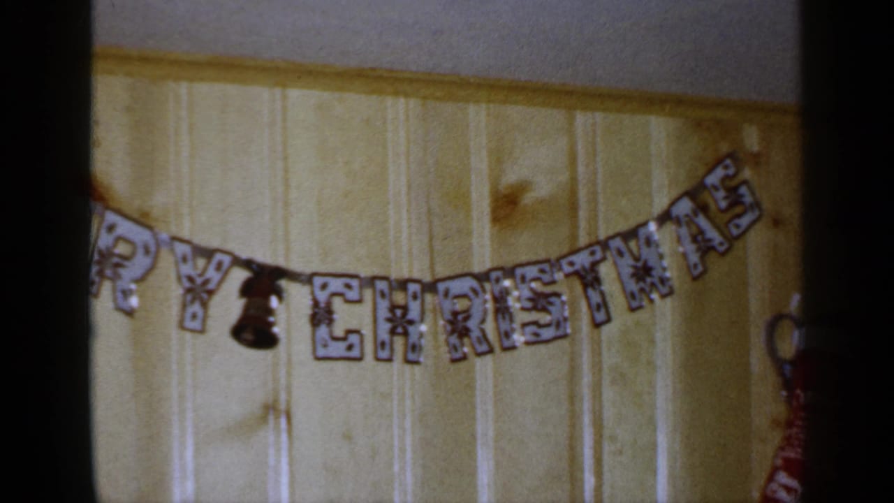 Partial Merry Christmas banner on a wood-paneled wall with dark film edges.
