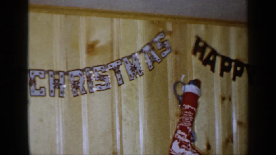 1965 Long Island frame showing the end of a Christmas banner, a hanging stocking, and the beginning of a Happy New Year banner.